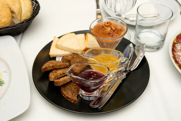 two types of jam and dessert with slices of sliced ​​white and black bread on a black plate
