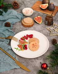 A plate of sliced traditional French foie gras decorated with fig fruit, red currant and rocket vegetable. With pot of onion marmalade in background and festive decoration atmosphere to celebrating  © Pkheawtasang