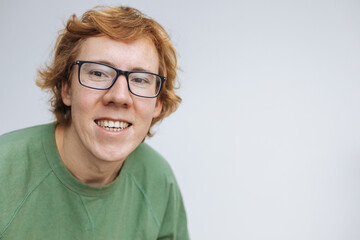 Red-haired man with glasses, smiling on a light background. copy space