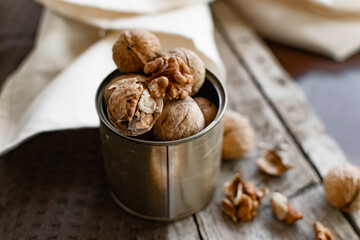 Walnuts in a tin of yellow metal next to the shell and the nuts on the inside. Decorated with dried oranges and a cinnamon stick. Composition of products and food on a wooden Board