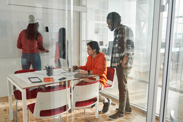 Diverse team of skilled young people learning web design while standing at the whiteboard