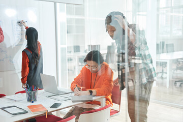 Multicultural diverse young people gather at table in classroom and discussing assignment