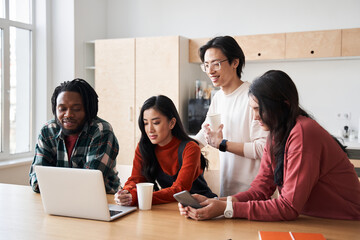 Focused young diverse team listening to teacher via internet connection