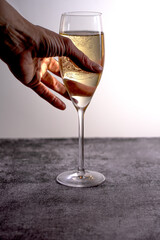 A young woman reaches for a golden glass of champagne.