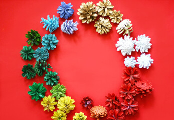 Christmas decoration of pinecones on a red background. Red, Yellow, Blue, green, white and golden cones.