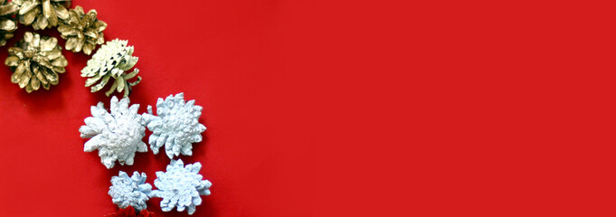 Christmas decoration of white cones on a red background. White and golden cones. Banner size