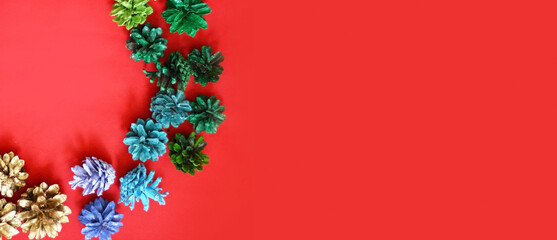 Christmas decoration of white cones on a red background. Blue, green, white and golden cones. Banner size