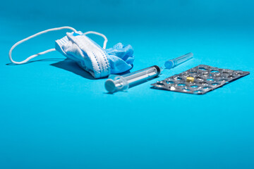 Blue face mask, pills, syringe on blue background. Medicine and healthcare. Medications and pharmacy. Low prespective.
