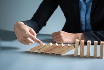 businessman hand taking Falling wooden Dominoes effect from continuous toppled or risk, strategy...