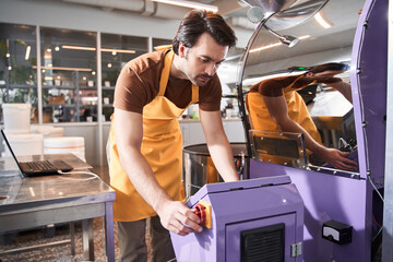 Man controlling coffee grounds roasting process