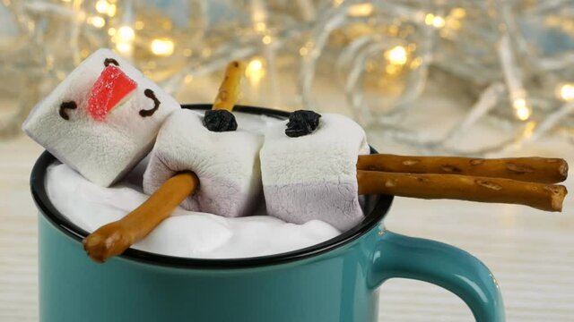 Marshmallow snowman in a mug of cocoa with whipped cream
