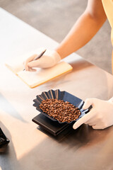 Seller in uniform weighing coffee beans