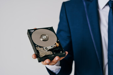 business man holding disassembled hard drive on gray background