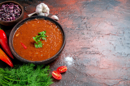 Tomato soup in a brown bowl and different spices garlic lemon on mixed color table stock image