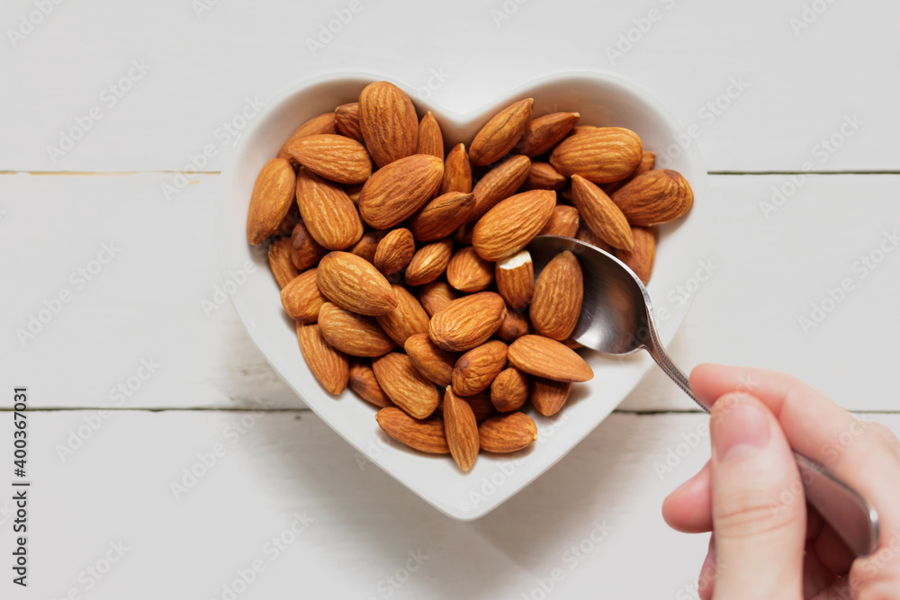 Canvas Prints top piece almond on heart-shaped plate, scoop the almonds from the plate on the wooden frame.