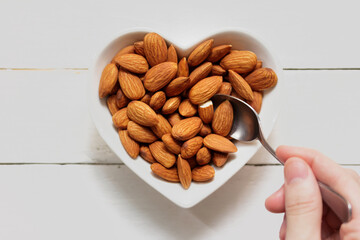 top piece almond on heart-shaped plate, scoop the almonds from the plate on the wooden frame.