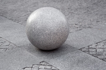 gray granite ball on the pedestrian sidewalk on a paving square with stone tiles, cityscape urban street architecture element, nobody.