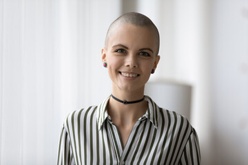 Headshot portrait of attractive millennial bald headed female musician informal person looking at...