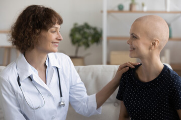 Optimistic female doctor giving psychological support to young woman receiving oncological...
