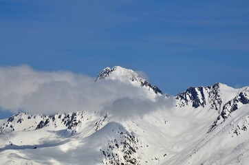 Winter landscape with mountain peaks, gorges, deep snow cover, ski slopes.