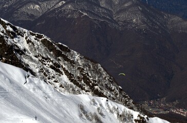 Winter landscape with mountain peaks, gorges, deep snow cover, ski slopes.