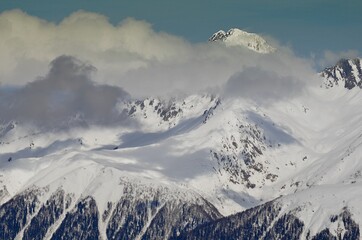 Winter landscape with mountain peaks, gorges, deep snow cover, ski slopes.