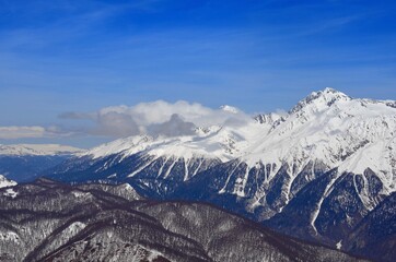 Winter landscape with mountain peaks, gorges, deep snow cover, ski slopes.