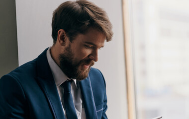 A business man in a suit with a tablet in his hands near the office manager window