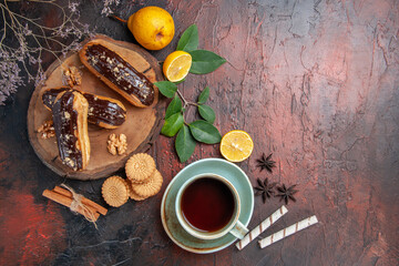 top view delicious choco eclairs with cup of tea on dark background dessert sweet cakes