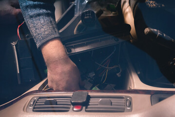 Car audio engineer is adjusting a car stereo system close up.