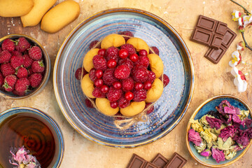Above view of hot herbal tea soft cake with fruits chocolate bars on mixed color table