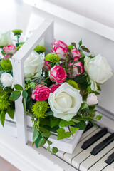 White wooden box with bouquet white and pink roses and chrysanthemums on white piano. Decoration of home. Flowers boxes. Wedding decoration