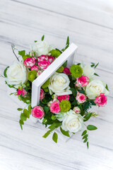 Wooden box with white and pink roses and chrysanthemums on  white wooden board. Decoration of home. Flowers boxes. Wedding decoration