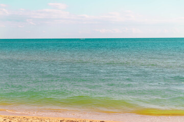 Beautiful emerald, turquoise sea with yellow sand and small waves.