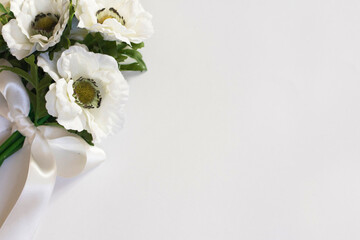 White flowers on a white background tied with a white satin ribbon