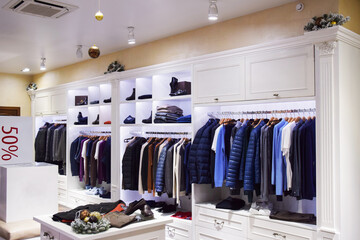New Year's decor in the salon of a men's clothing store. Christmas shop window decoration. Decorated shop with balls and snow branches.