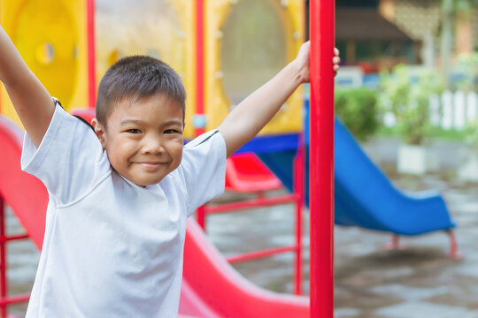 Portrait image of 6-7 years old boy. Happy Asian child boy play the toy and climbing the steel toy bar at the playground. He smiling. Sport and exercise of kid.