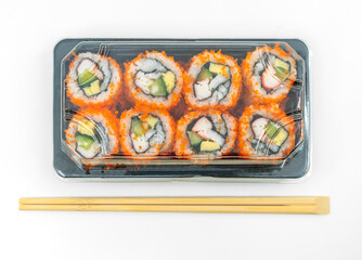Top view Sushi rolls ready to eat in plastic container with chopsticks, isolated image on white background.