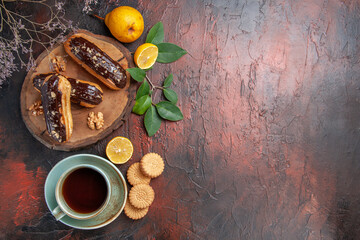 top view yummy choco eclairs with cup of tea on dark background dessert sweet cake