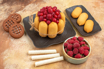 A gift cake and biscuits on brown plates fruits on mixed color background side view