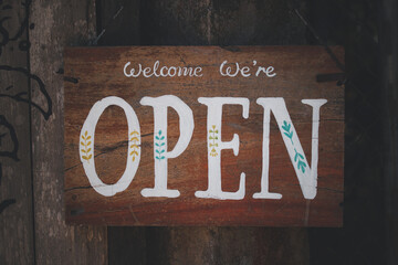 Open sign on old wooden with art bouquetyes "Welcome we're open" sign, open sign in street cafe, vintage style restaurant sign.