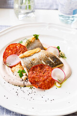 Pike perch fillet with chorizo, cauliflower and radish in a restaurant serving. Close up. Keto, paleo, fodmap diet food.