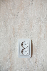 Double socket in the wall against wallpaper.