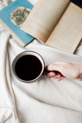 Coffee in hands on the background of books.