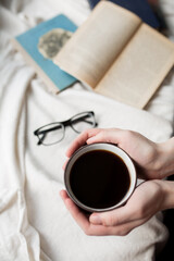 Coffee in hands on the background of books.