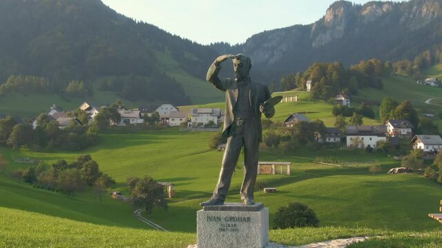 Lovely lush green rural landscape surrounds a bronze life-size statue of Ivan Grohar a Slovene painter. Weathered statue of a famous Slovenian painter is surrounded by the golden-lit countryside.