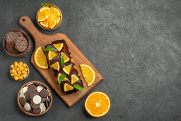 Above view of tasty cakes cut lemons with biscuits on cutting board on dark table