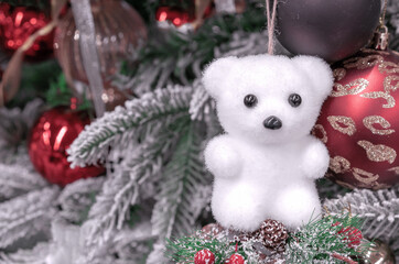 Little white bear cub on a snow-covered Christmas tree.