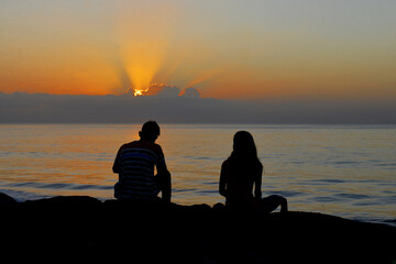 Silhouette of a couple enjoy sunrise at Matahari Beach in Bali Island, Indonesia.