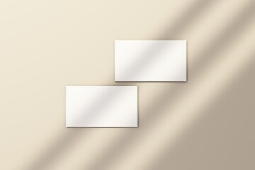 Blank white business card on white floor with rays of sunlight 